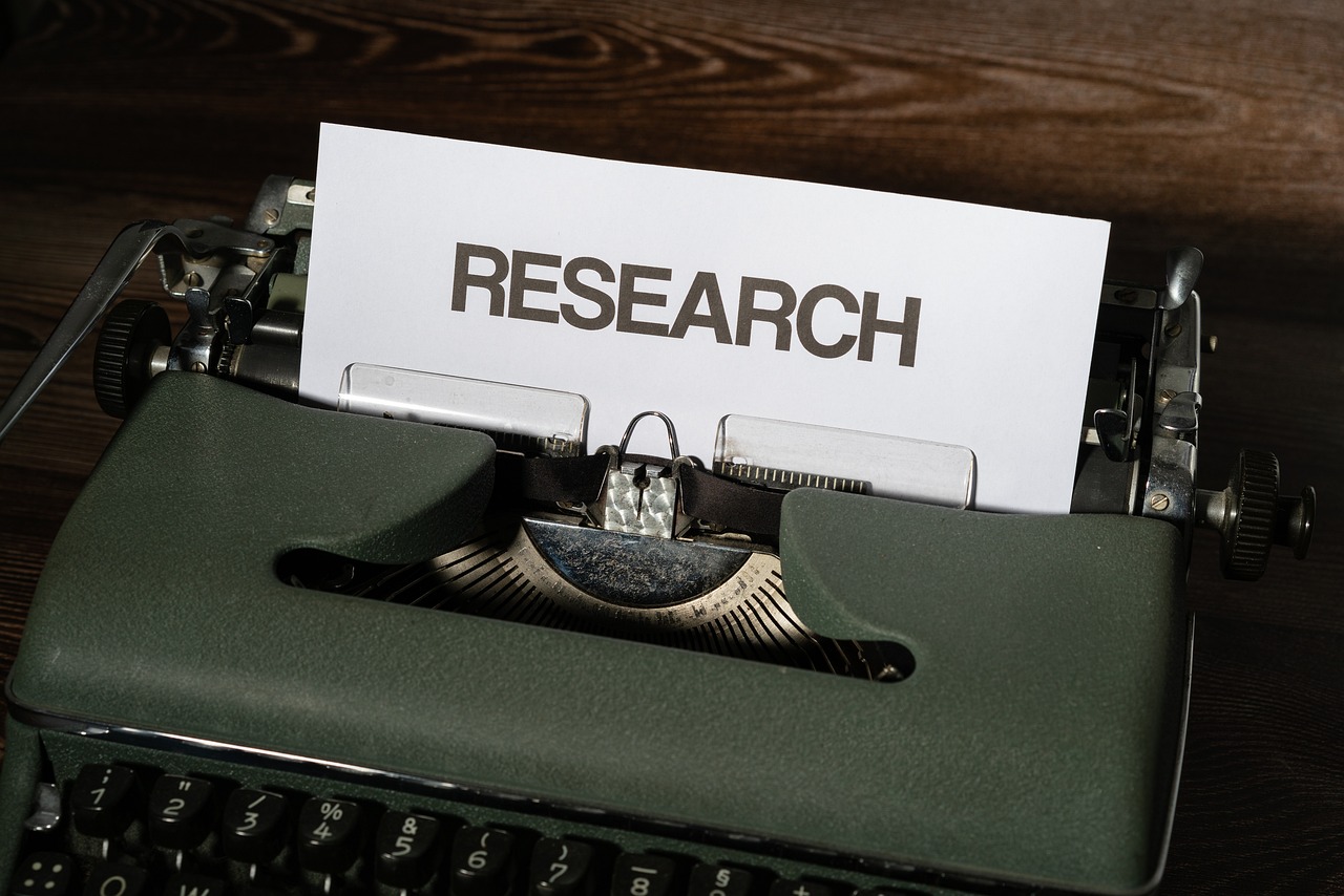 Picture of a green typewriter with the word "research" typed onto a page.