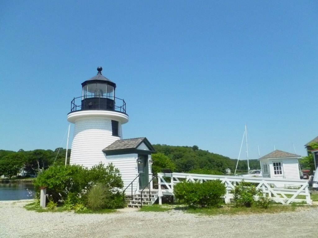 Picture of a white lighthouse surrounded by green bushes. 